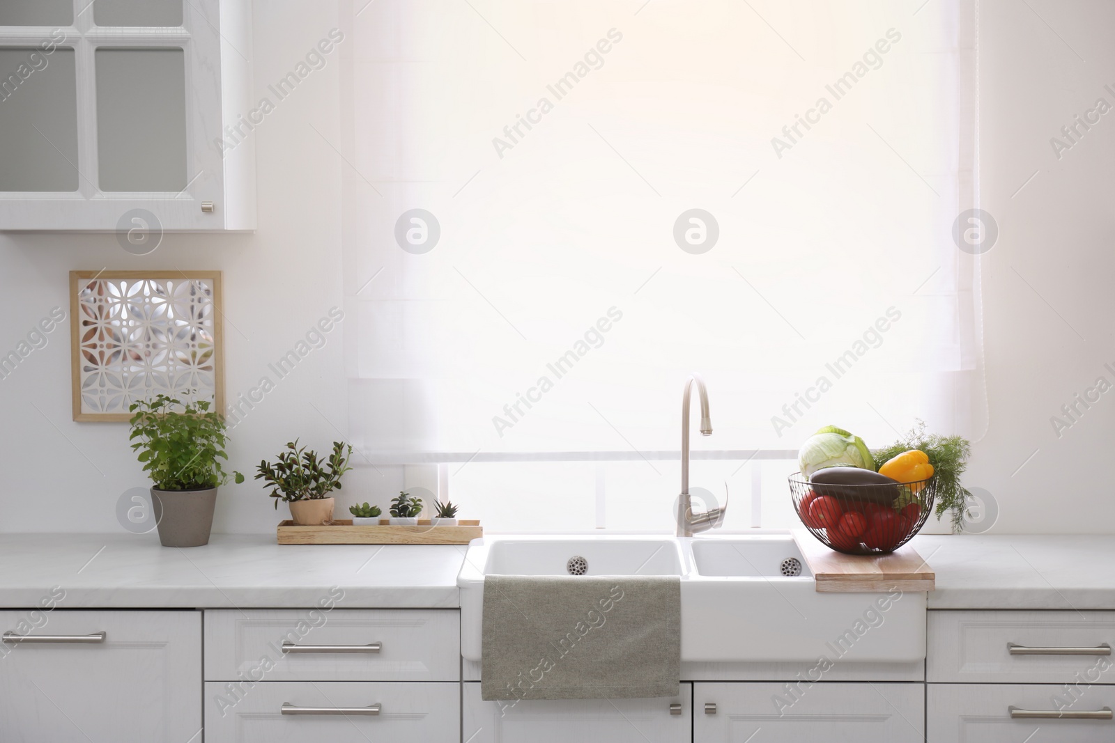Photo of Basket full of different vegetables on wooden board in modern kitchen