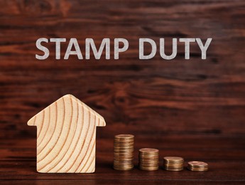 Image of Stamp duty. House model and coins on wooden background