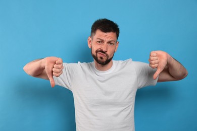 Photo of Man showing thumbs down on light blue background