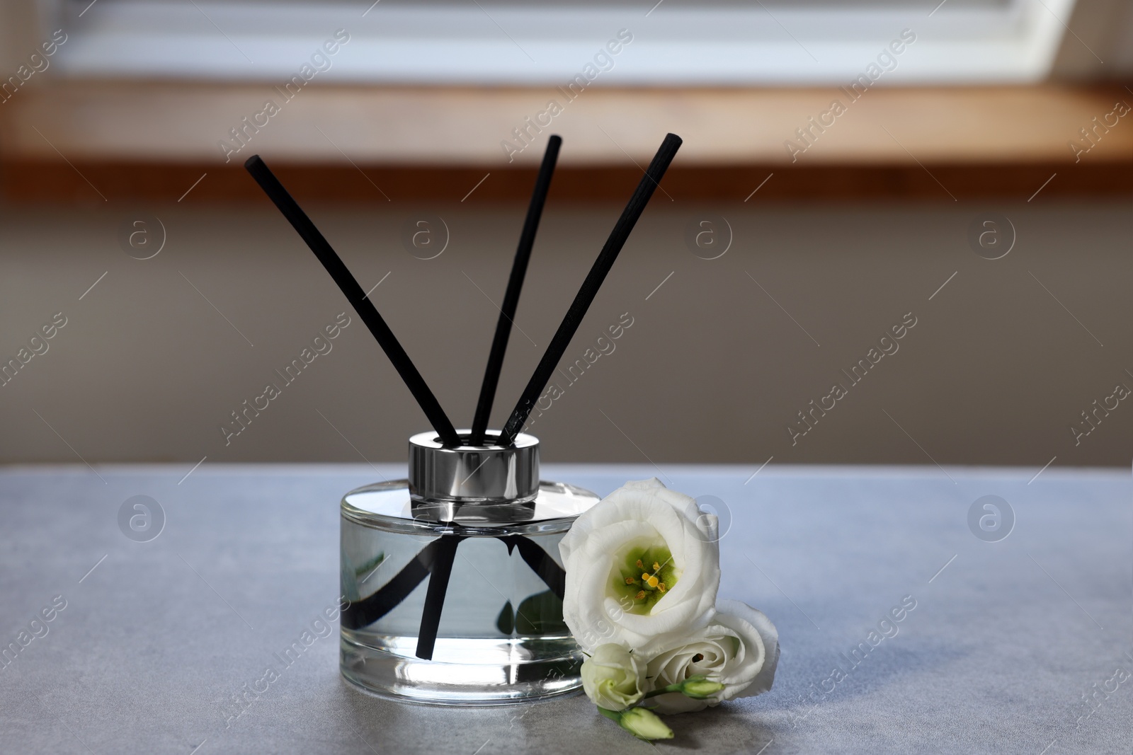 Photo of Reed diffuser and eustoma flowers on gray marble table