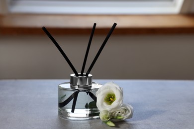 Reed diffuser and eustoma flowers on gray marble table