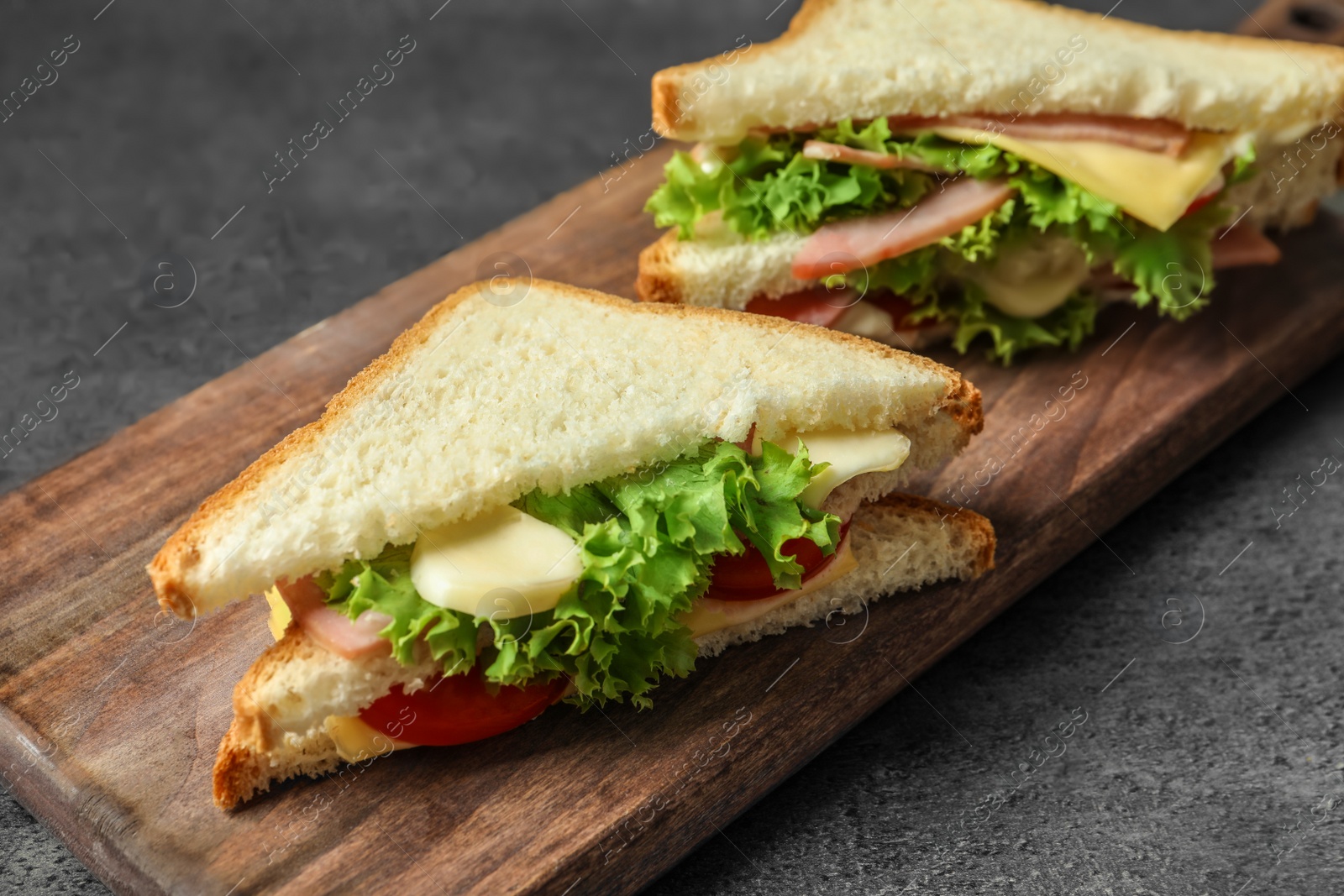 Photo of Tasty toast sandwiches on wooden board. Wheat bread