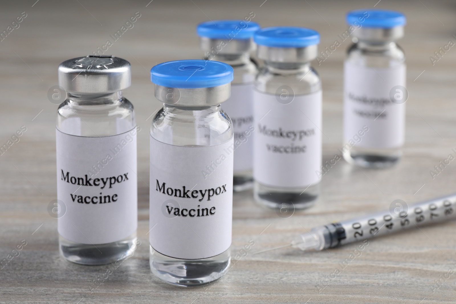 Photo of Monkeypox vaccine in glass vials and syringe on wooden table