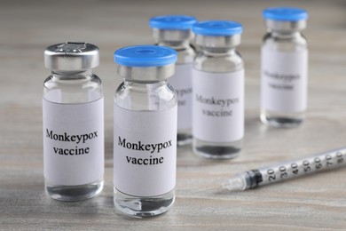 Monkeypox vaccine in glass vials and syringe on wooden table