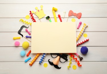 Flat lay composition with carnival items and blank card on white wooden background. Space for text