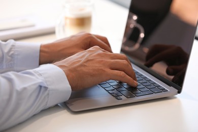 Photo of Man using modern laptop at white desk, closeup