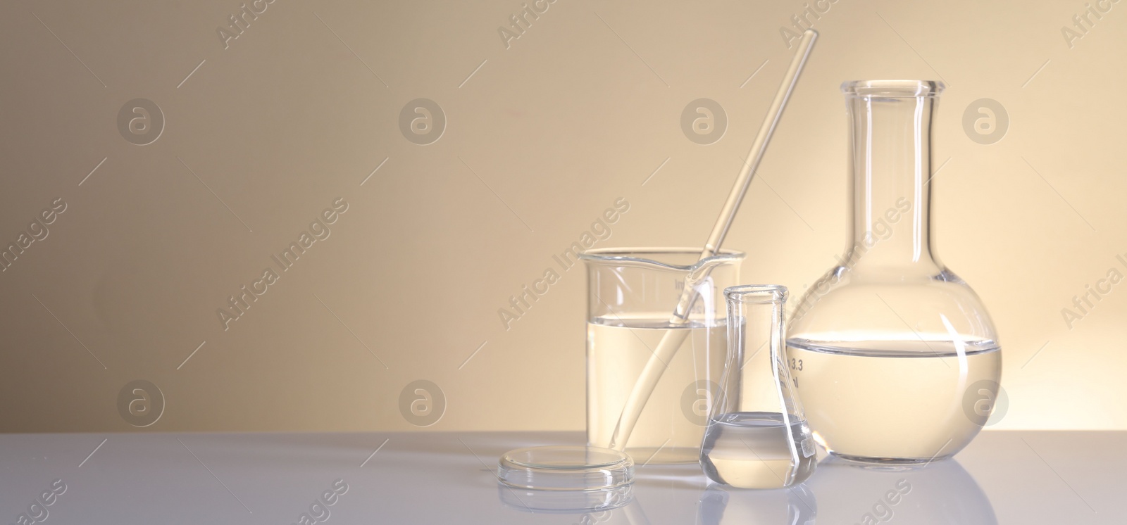 Photo of Laboratory analysis. Different glassware on table against beige background, space for text