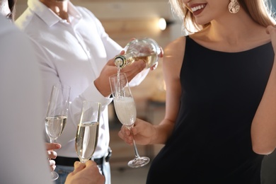 Man pouring champagne into glasses at party indoors, closeup