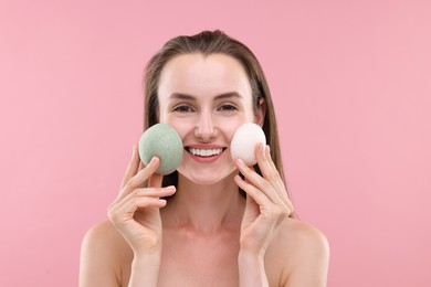 Happy young woman with face sponges on pink background