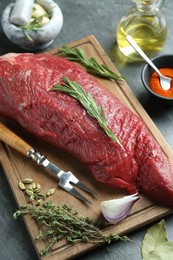 Photo of Piece of raw beef meat and spices on grey table