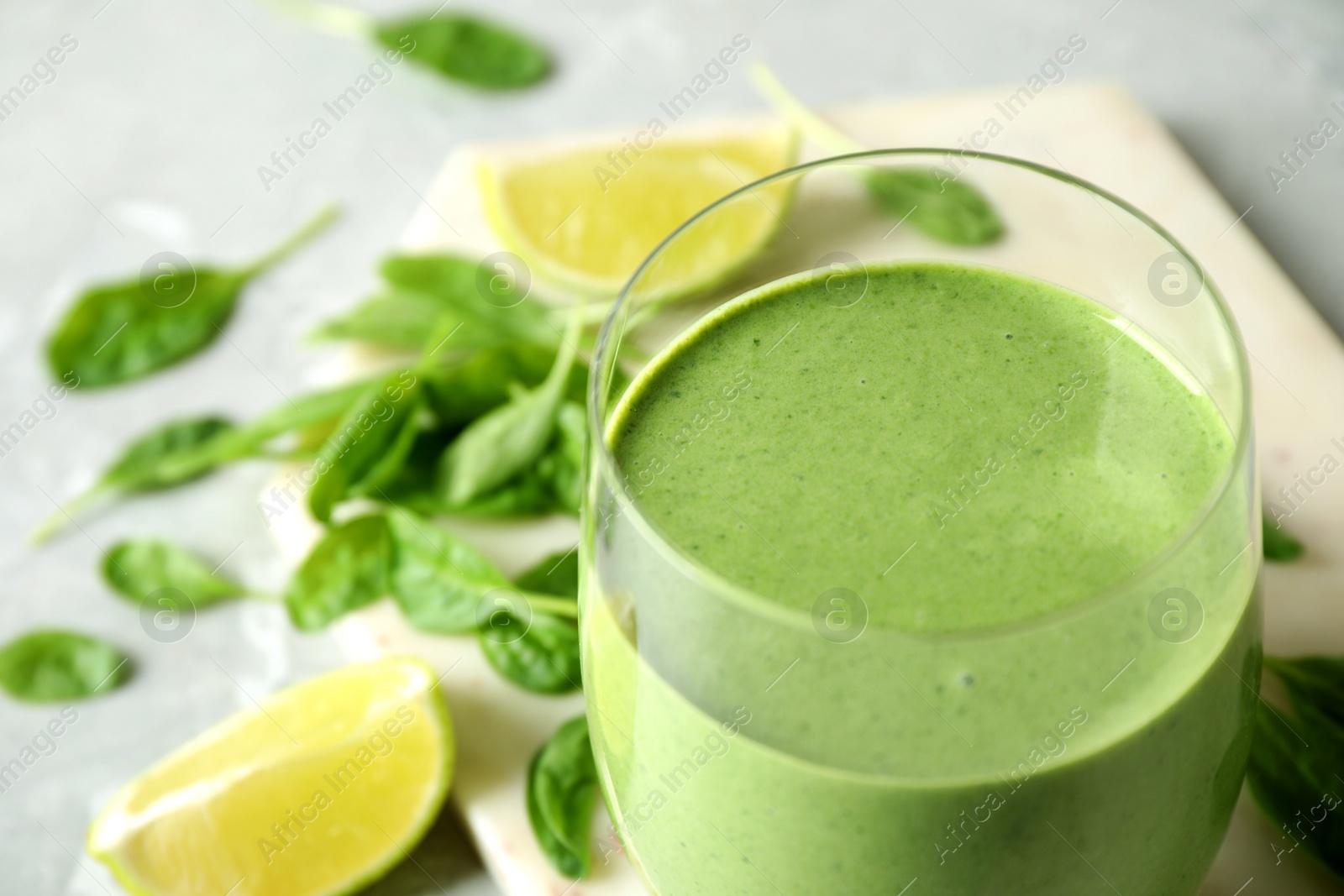 Photo of Glass of healthy green smoothie with fresh spinach on table, closeup