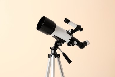 Photo of Tripod with modern telescope on beige background, closeup