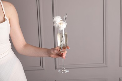 Photo of Woman holding glass of cotton candy cocktail near grey wall, closeup. Space for text