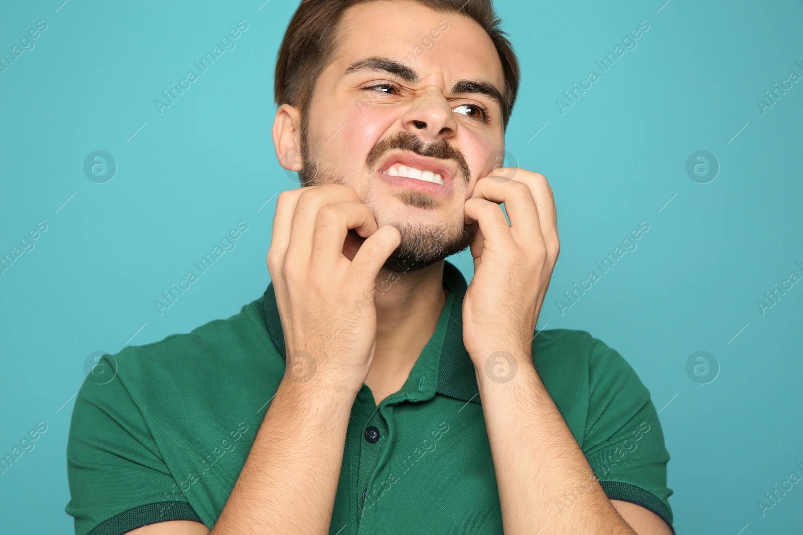 Photo of Young man scratching face on color background. Annoying itch