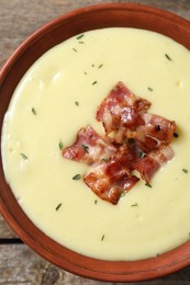 Tasty potato soup with bacon and rosemary in bowl on table, top view