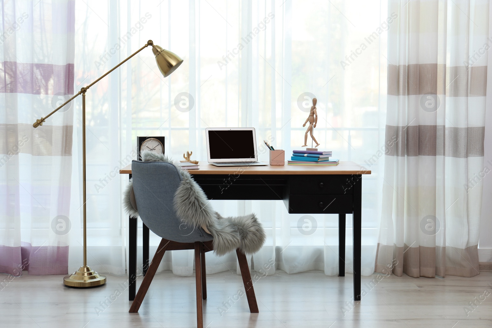 Photo of Stylish workplace interior with laptop on table near window. Space for text