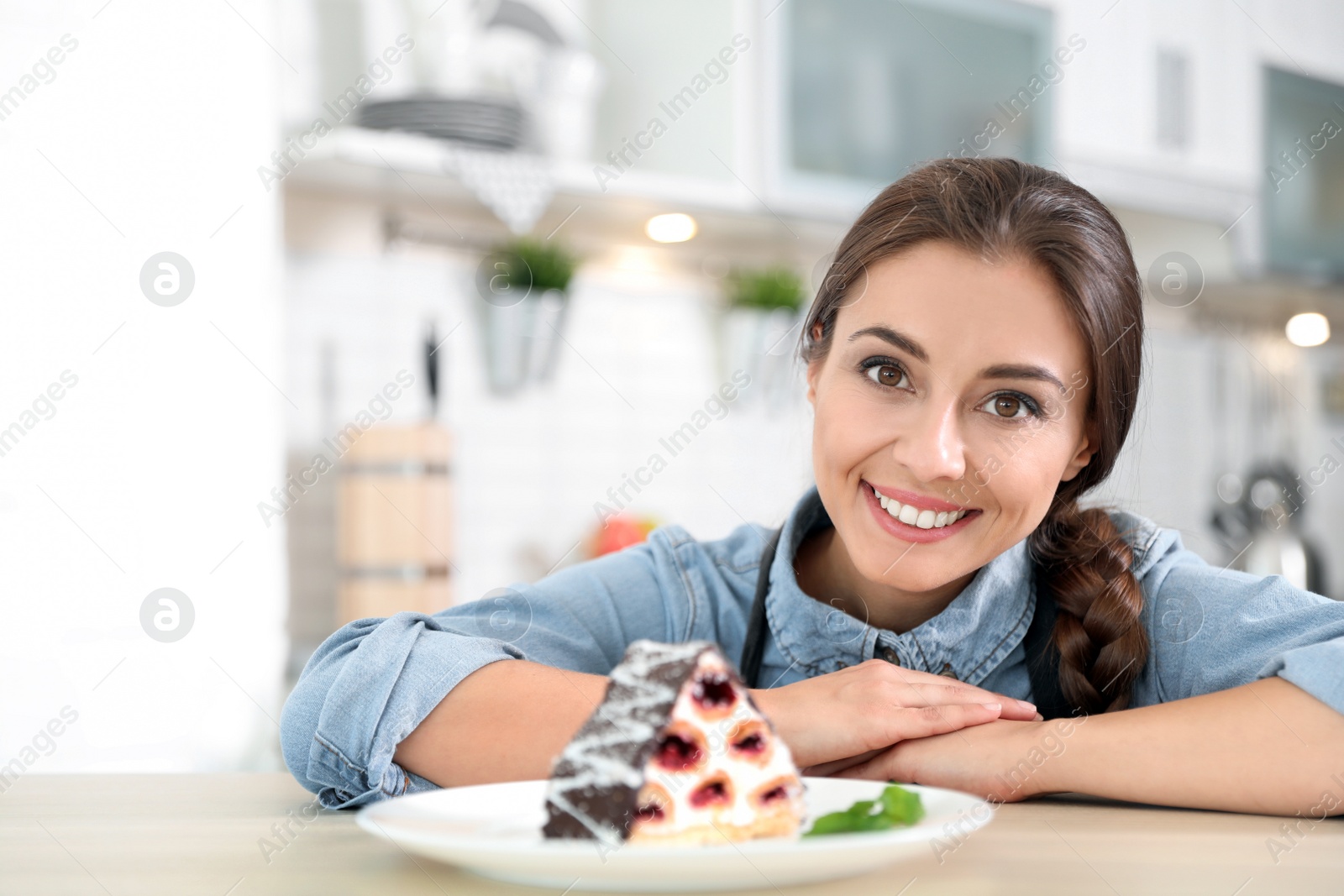 Photo of Professional female chef presenting dessert on table in kitchen