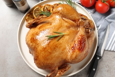 Photo of Tasty roasted chicken with rosemary and knife on light grey table, flat lay