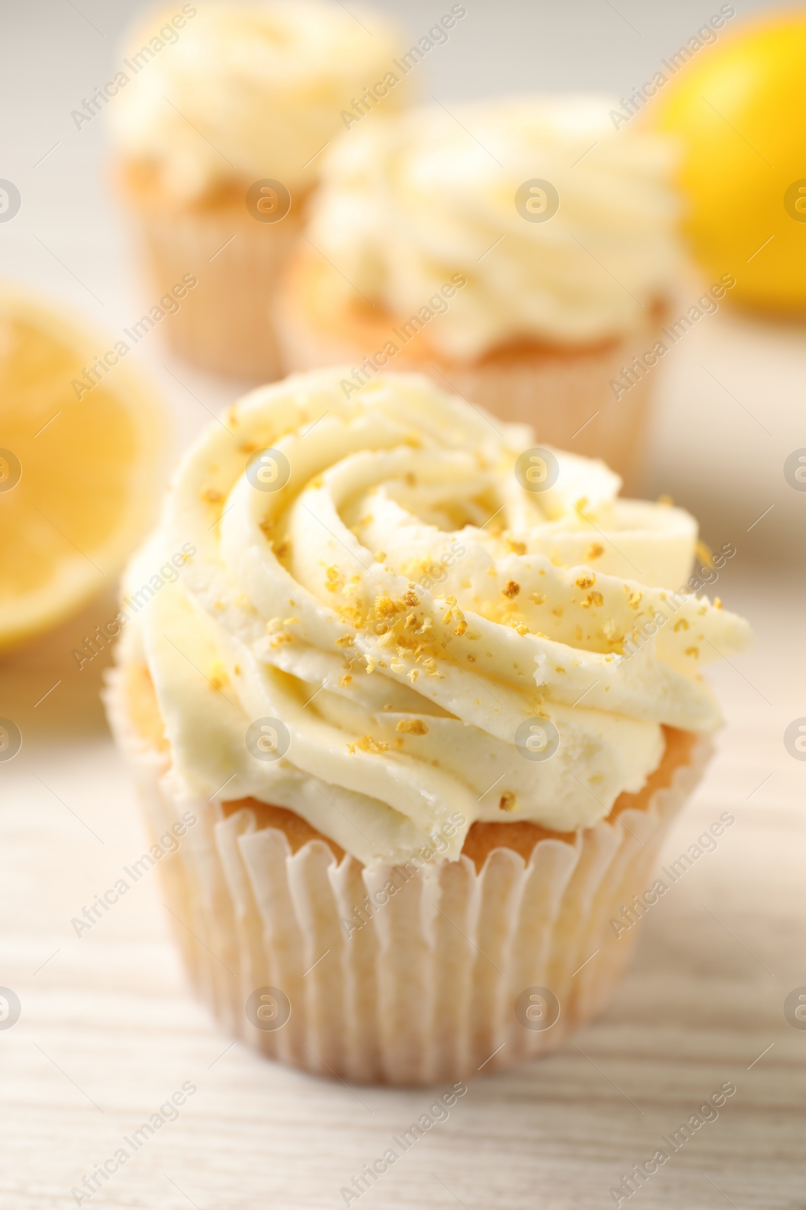 Photo of Tasty cupcake with cream and lemon zest on white wooden table, closeup