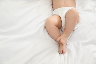 Photo of Cute little baby in diaper on bed, top view. Space for text