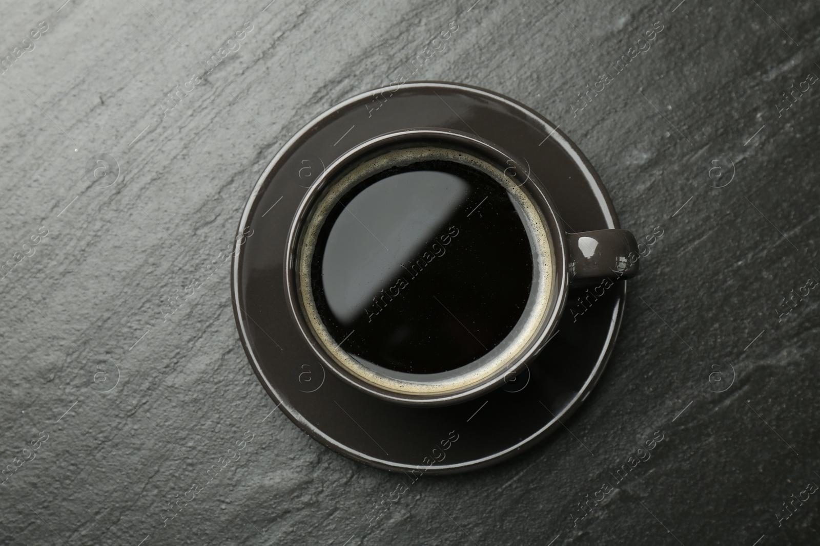 Photo of Hot coffee in cup on dark textured table, top view