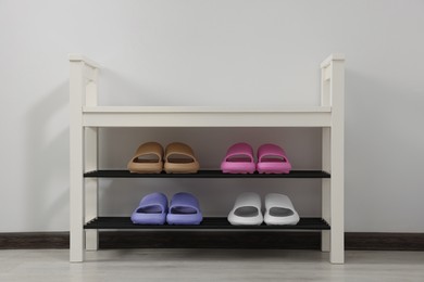Photo of Storage bench with pairs of rubber slippers indoors