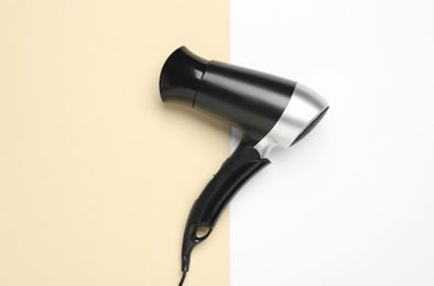 Photo of Hair dryer on color background, top view. Professional hairdresser tool