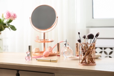 Photo of Dressing table with different makeup products and accessories in room interior