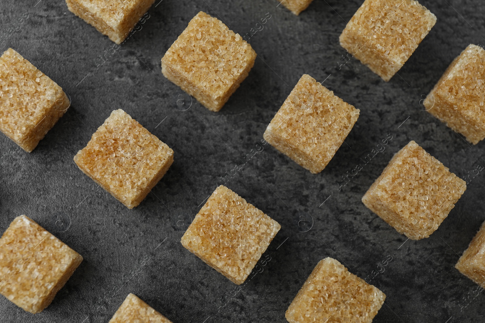 Photo of Brown sugar cubes on grey table, flat lay