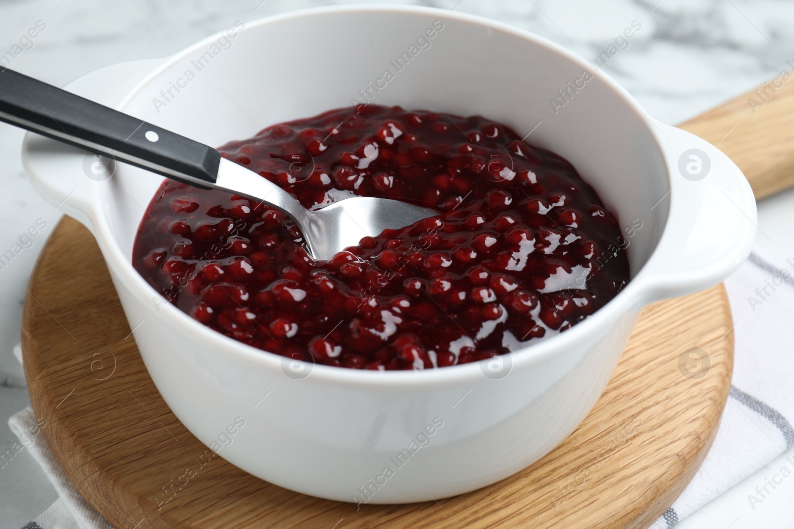 Photo of Fresh cranberry sauce in bowl served on table, closeup