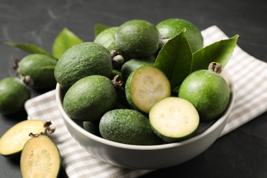 Photo of Fresh green feijoa fruits in bowl on black table, closeup