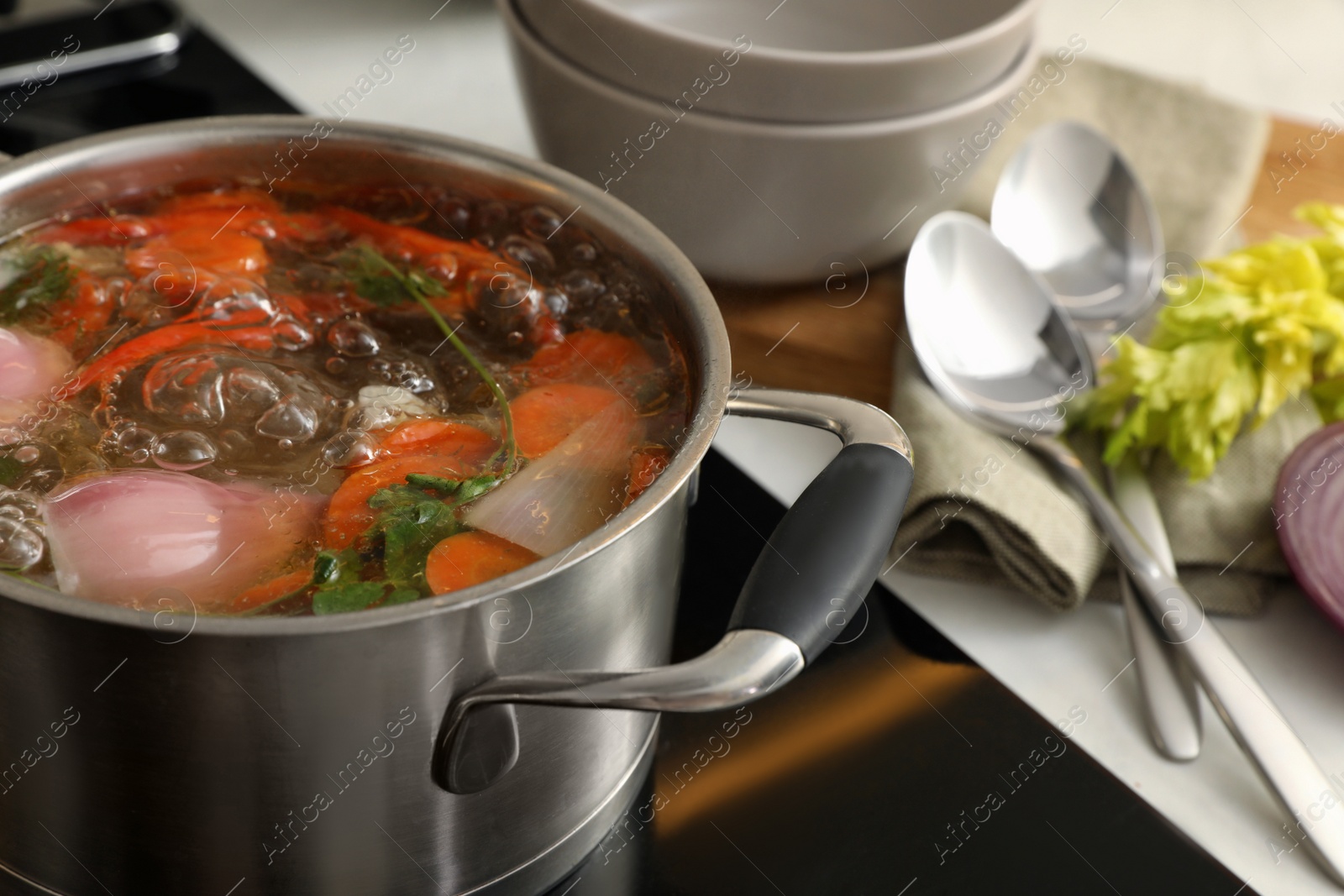 Photo of Pot of delicious vegetable bouillon on stove in kitchen, closeup