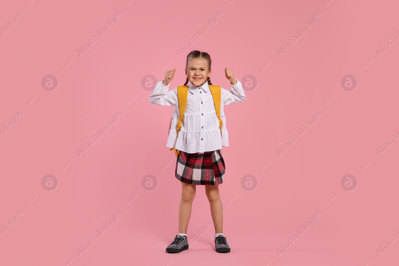 Photo of Happy schoolgirl with backpack on pink background