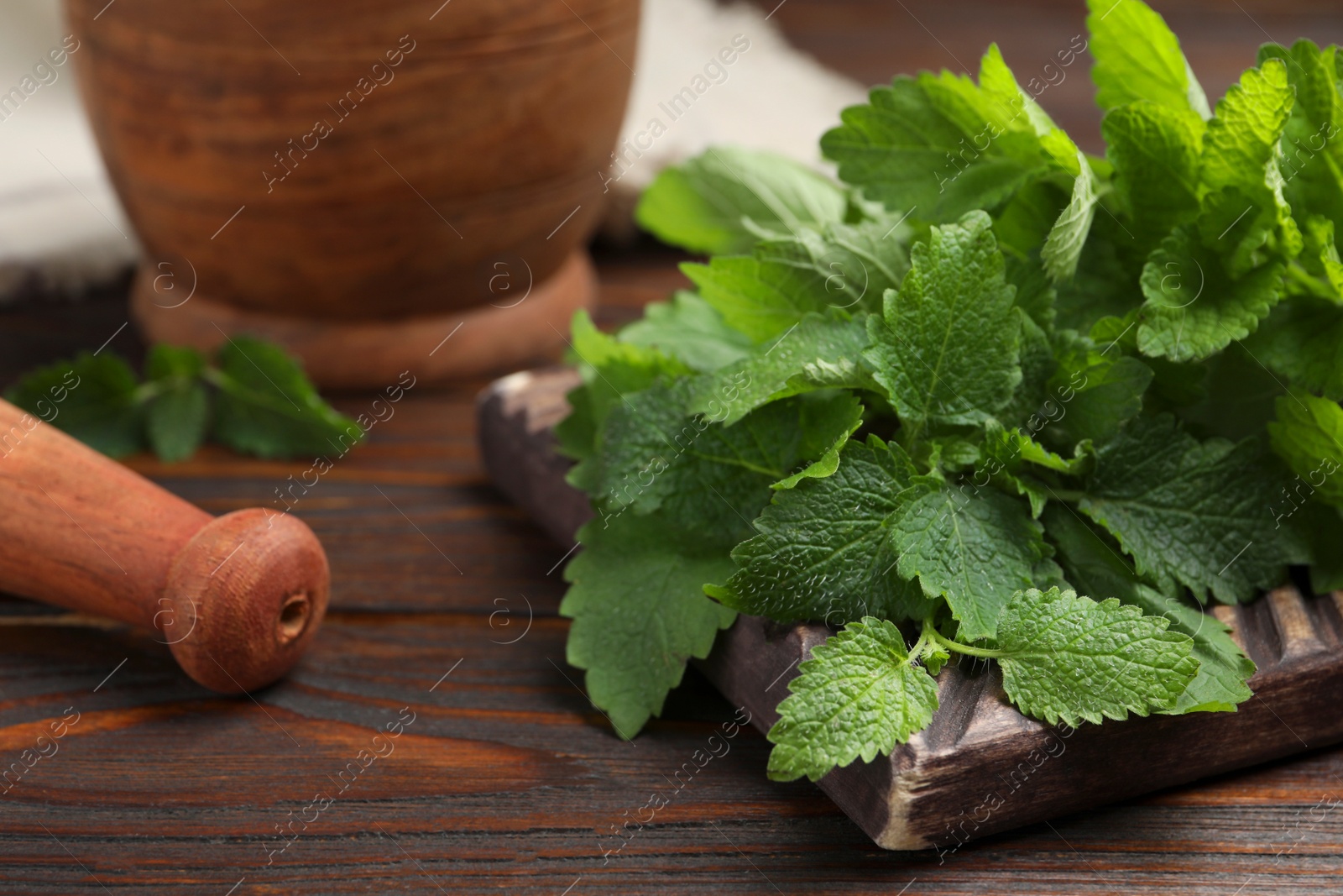 Photo of Fresh green lemon balm leaves on wooden table, closeup