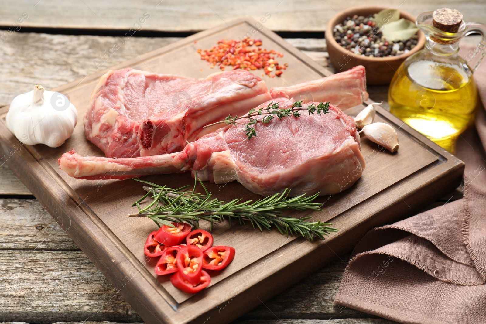 Photo of Fresh tomahawk beef cuts and spices on wooden table