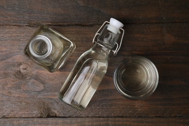 Vinegar in bottles and glass on wooden table, flat lay