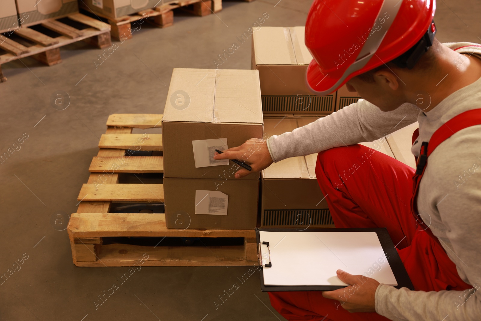 Image of Worker holding clipboard near pallet with boxes in warehouse