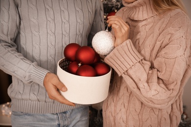 Couple with box of Christmas balls indoors, closeup