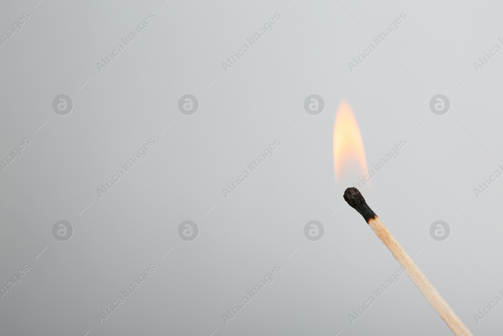 Photo of Burning match on grey background, space for text