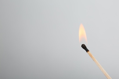 Photo of Burning match on grey background, space for text