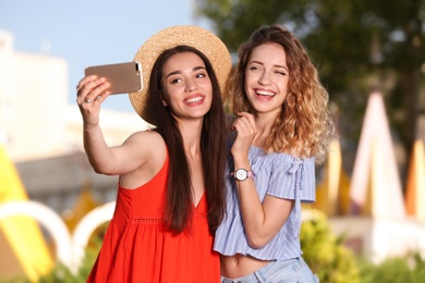 Photo of Happy young women taking selfie outdoors on sunny day