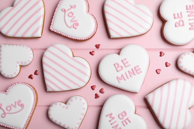 Photo of Decorated heart shaped cookies on pink table, flat lay. Valentine's day treat