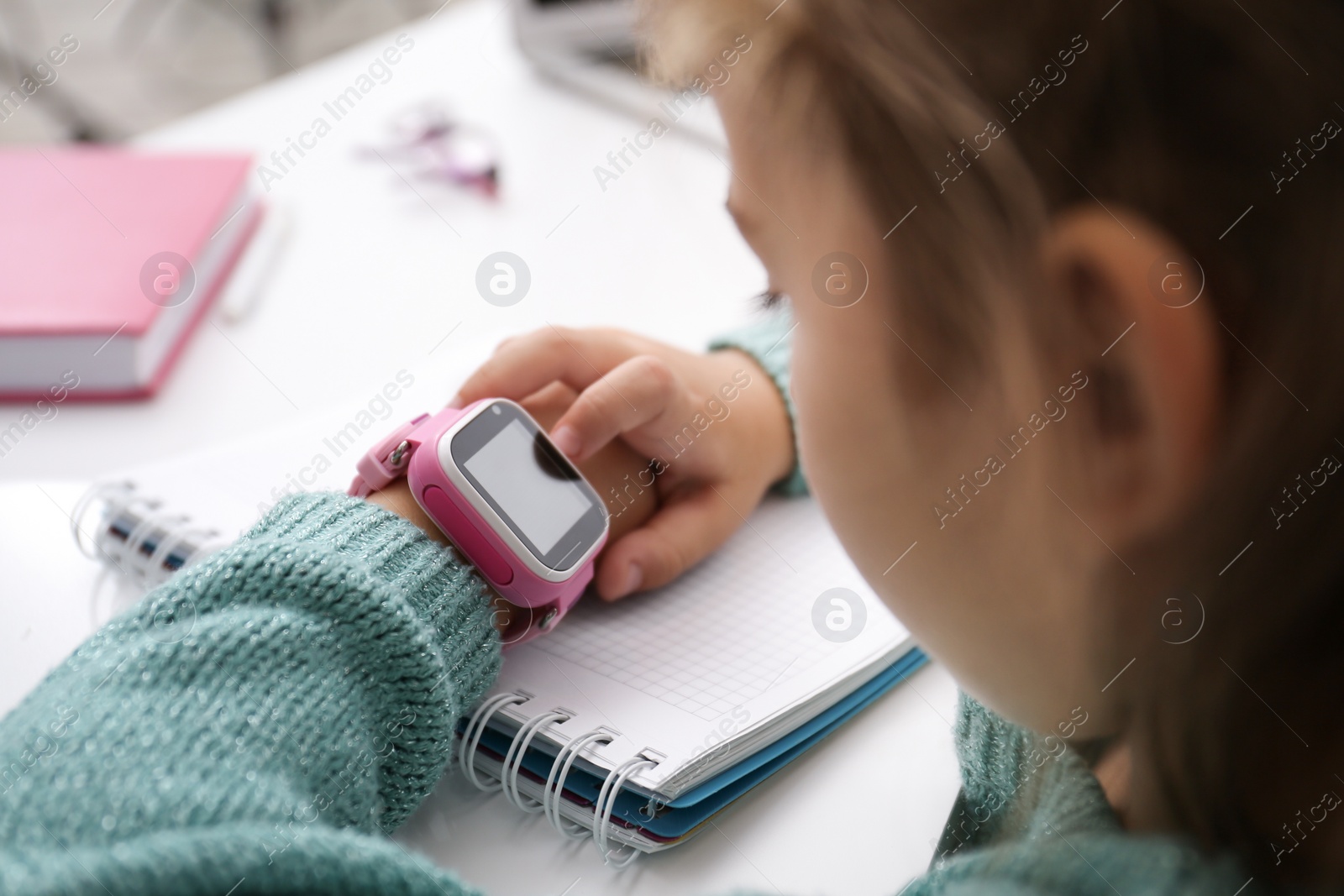 Photo of Girl with stylish smart watch at table, closeup