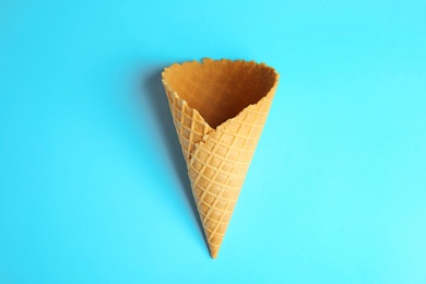 Photo of Empty wafer ice cream cone on blue background, top view