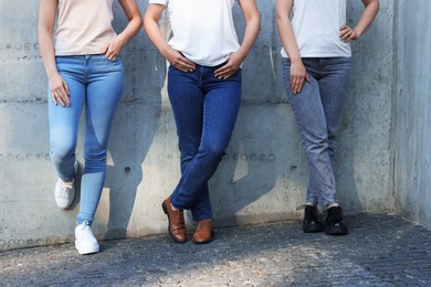 Photo of Women in stylish jeans near grey wall outdoors, closeup