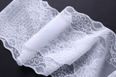 Photo of White lace on black background, top view