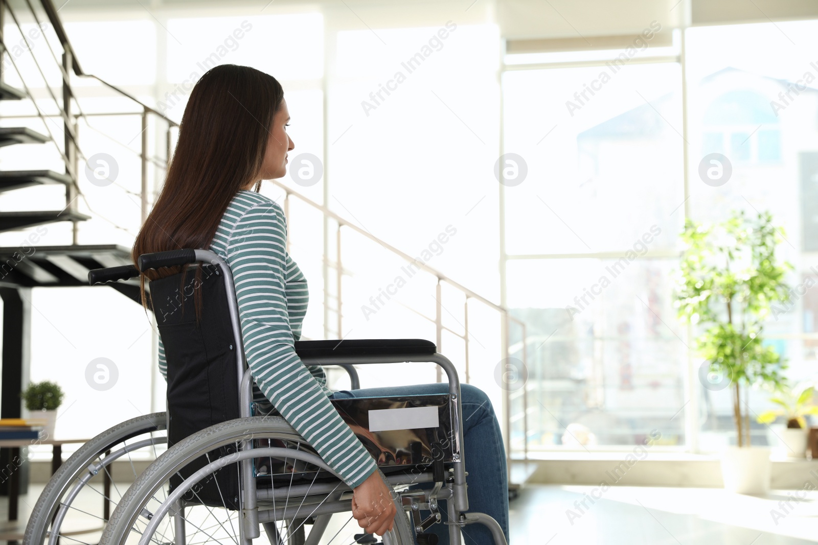 Photo of Young woman in wheelchair indoors. Space for text