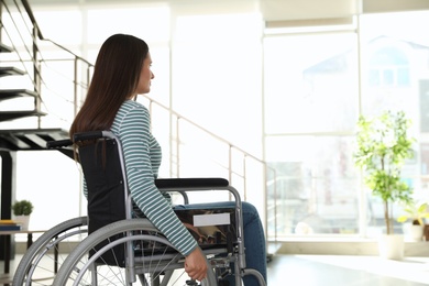 Photo of Young woman in wheelchair indoors. Space for text