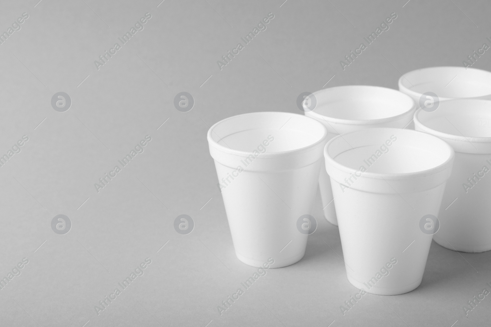 Photo of Many styrofoam cups on light grey background, space for text