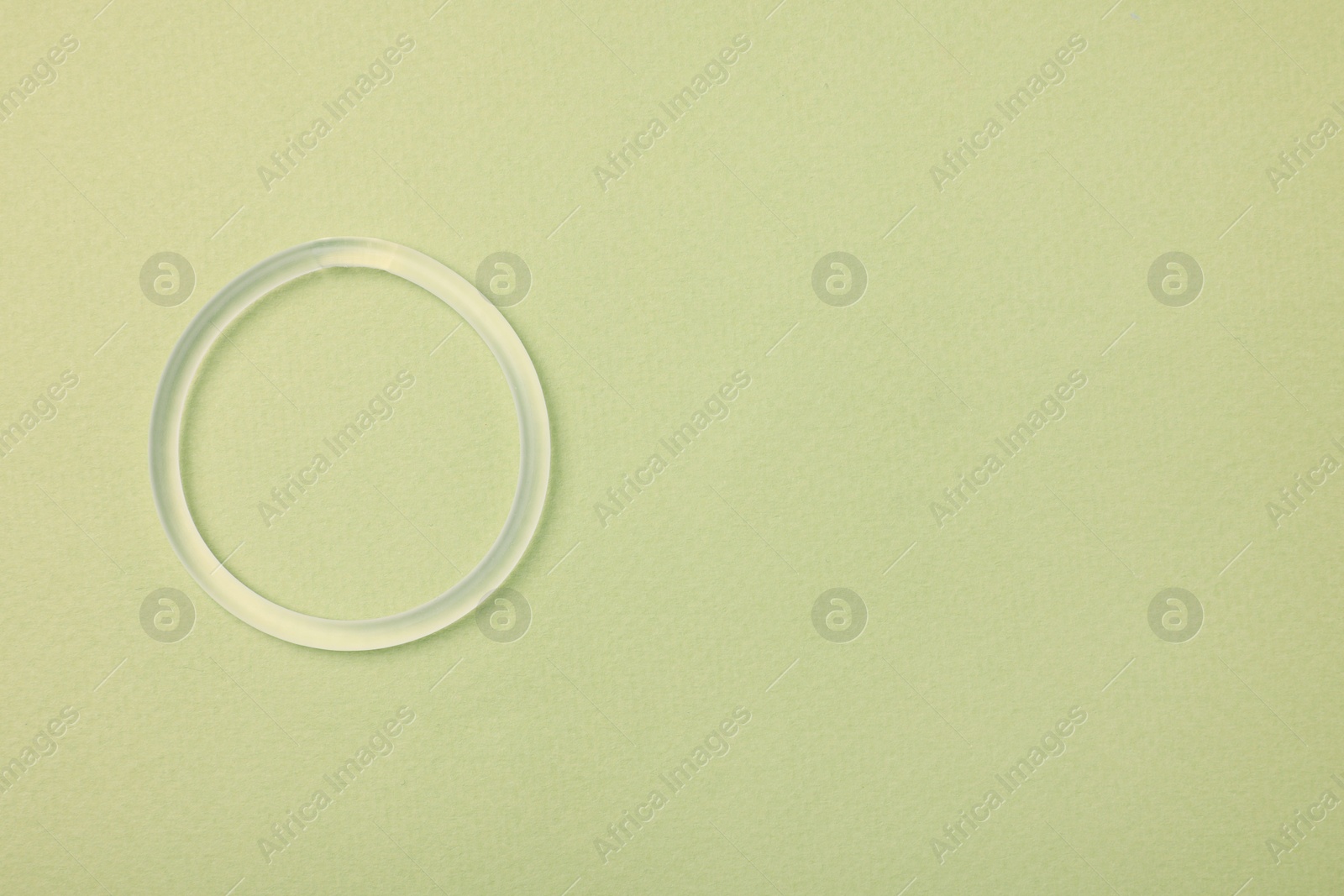Photo of Diaphragm vaginal contraceptive ring on light green background, top view. Space for text